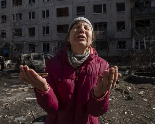 Ukrainian woman in front of bombed building